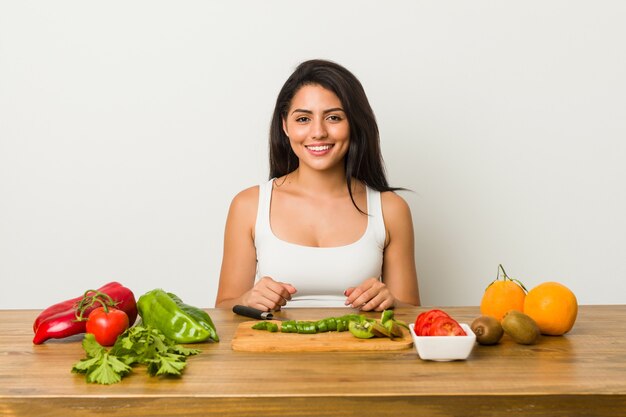 Jovem hispânica cortando legumes na mesa