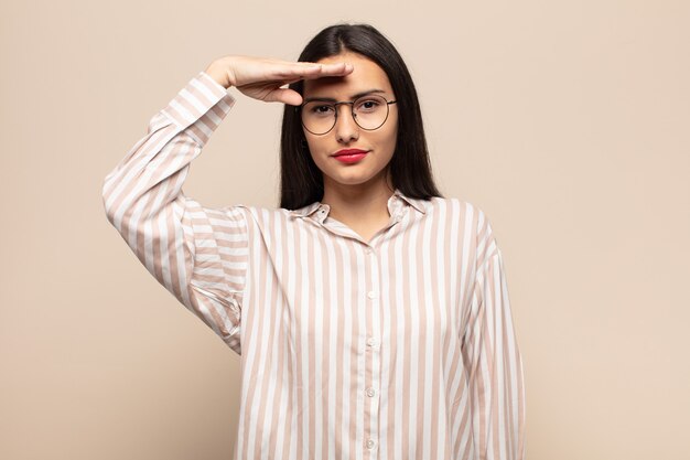 Jovem hispânica cumprimentando a câmera com uma saudação militar em um ato de honra e patriotismo, mostrando respeito