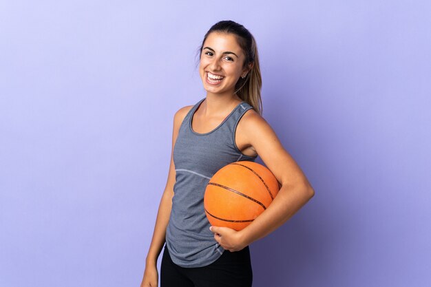 Jovem hispânica em uma parede roxa isolada jogando basquete