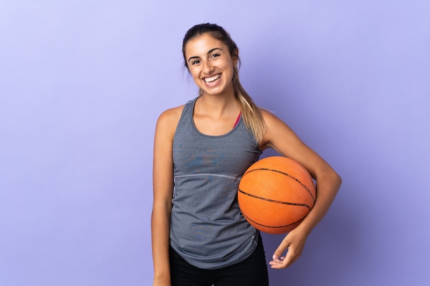 Jovem hispânica em uma parede roxa isolada jogando basquete