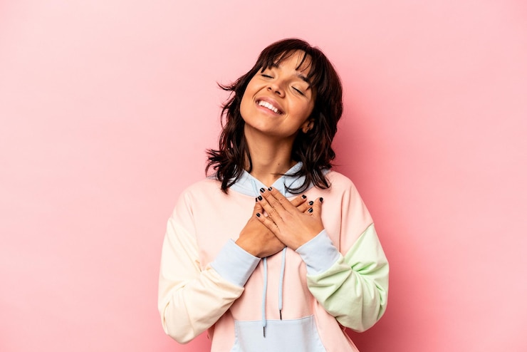 Foto jovem hispânica isolada em fundo rosa tem expressão amigável pressionando a palma da mão no peito conceito de amor