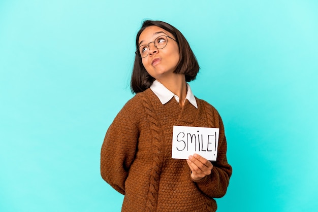 Jovem hispânica isolada segurando um cartaz de sorriso