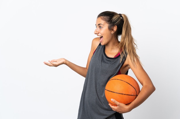 Jovem hispânica jogando basquete sobre uma parede branca isolada com expressão de surpresa enquanto olha para o lado