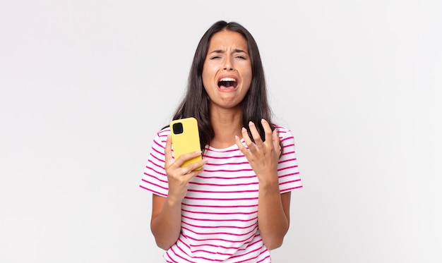 jovem hispânica parecendo desesperada, frustrada e estressada, segurando um smartphone
