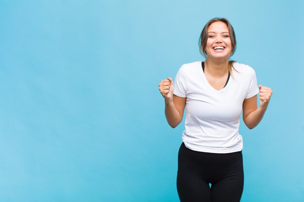 Jovem hispânica parecendo extremamente feliz e surpresa, comemorando o sucesso, gritando e pulando