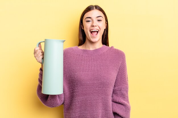 Jovem hispânica parecendo feliz e agradavelmente surpresa. conceito de garrafa térmica de café