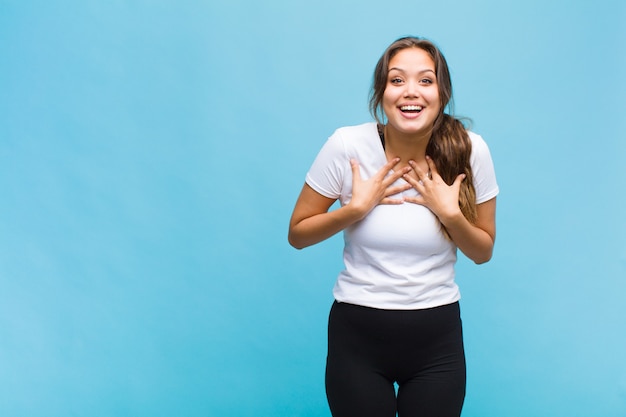 Jovem hispânica parecendo feliz, surpresa, orgulhosa e animada, apontando para si mesma