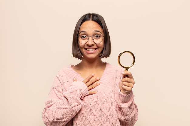 Jovem hispânica parecendo feliz, surpresa, orgulhosa e animada, apontando para si mesma