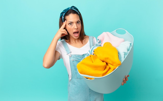 Jovem hispânica parecendo surpresa, percebendo um novo pensamento, ideia ou conceito e lavando roupa