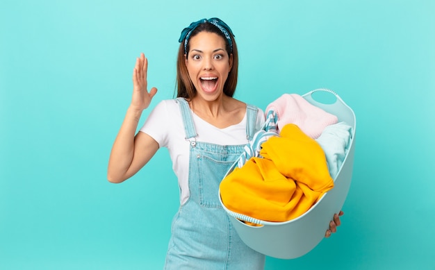 Foto jovem hispânica se sentindo feliz e surpresa com algo inacreditável e lavando roupas