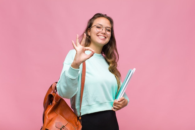 Jovem hispânica se sentindo feliz, relaxada e satisfeita, mostrando aprovação com um gesto de ok, sorrindo