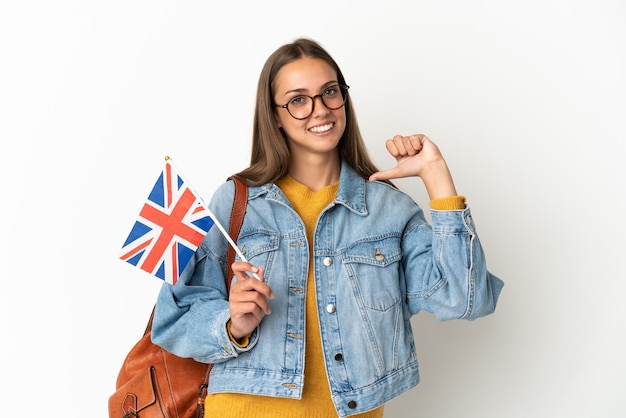 Jovem hispânica segurando uma bandeira do reino unido sobre um fundo branco isolado, orgulhosa e satisfeita