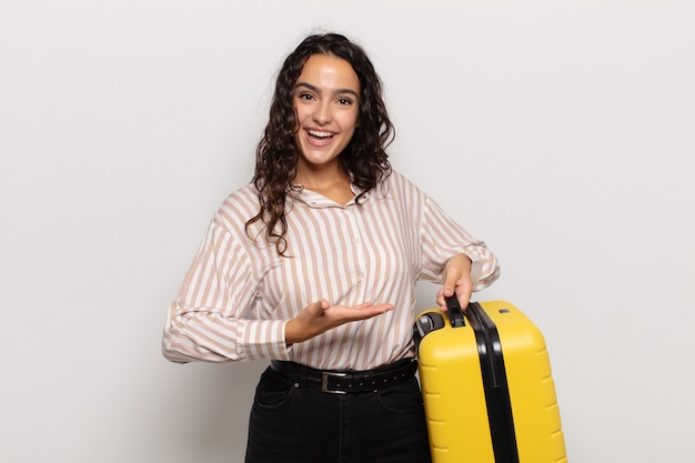 Jovem hispânica sorrindo alegremente, se sentindo feliz e mostrando um conceito no espaço da cópia com a palma da mão