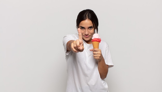 Jovem hispânica sorrindo com orgulho e confiança fazendo a pose número um triunfantemente, sentindo-se uma líder