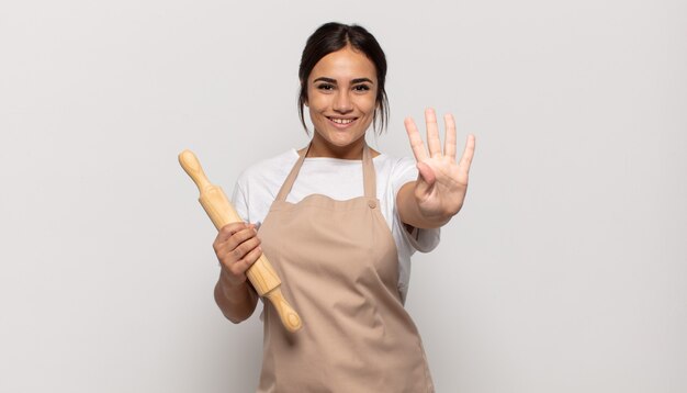 Jovem hispânica sorrindo e parecendo amigável, mostrando o número quatro ou o quarto com a mão para a frente, em contagem regressiva