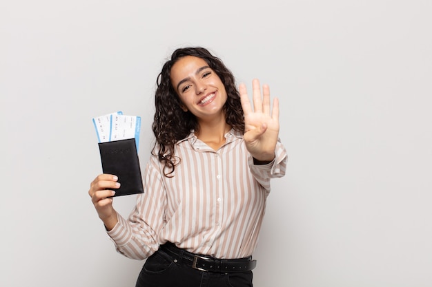 Jovem hispânica sorrindo e parecendo amigável, mostrando o número quatro ou o quarto com a mão para a frente, em contagem regressiva