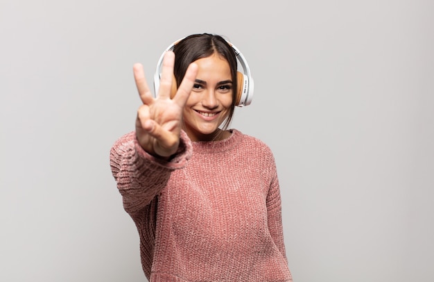 Jovem hispânica sorrindo e parecendo amigável, mostrando o número três ou terceiro com a mão para a frente, em contagem regressiva