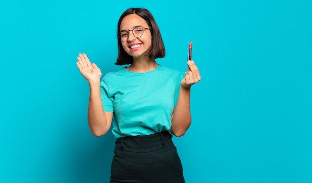 Jovem hispânica sorrindo feliz e animada, acenando com a mão, dando as boas-vindas e cumprimentando você ou dizendo adeus