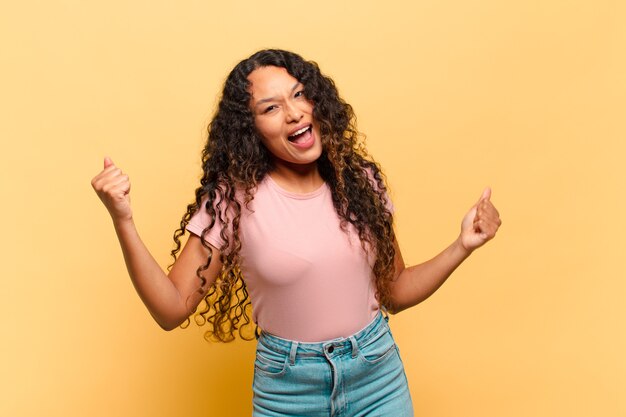 jovem hispânica sorrindo, sentindo-se despreocupada, relaxada e feliz, dançando e ouvindo música, se divertindo em uma festa