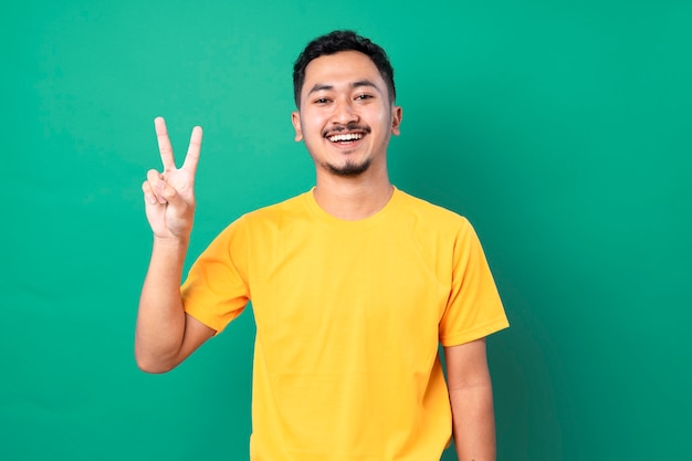 Jovem hispânico alegre e despreocupado mostrando um símbolo da paz com os dedos