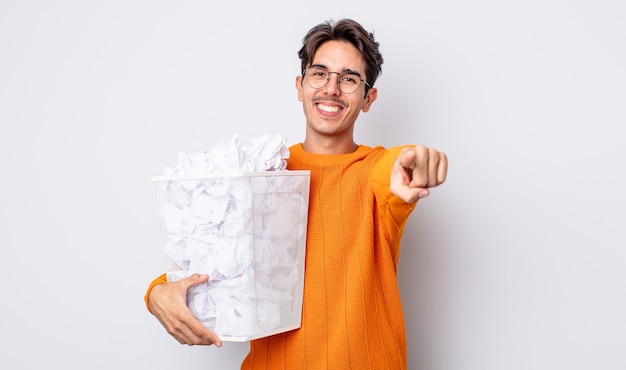 Jovem hispânico apontando para a câmera escolhendo você. conceito de lixo de bolas de papel