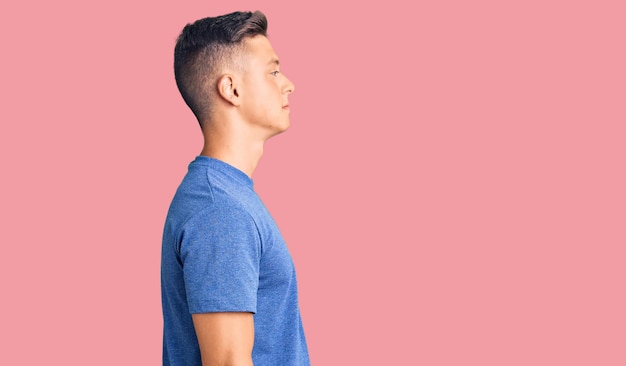 Jovem hispânico bonito vestindo roupas casuais olhando para o lado relaxar pose de perfil com rosto natural com sorriso confiante