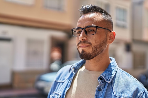 Jovem hispânico com expressão relaxada usando óculos na rua