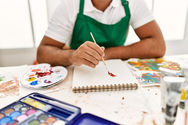 Jovem hispânico desenhando em notebook no estúdio de arte