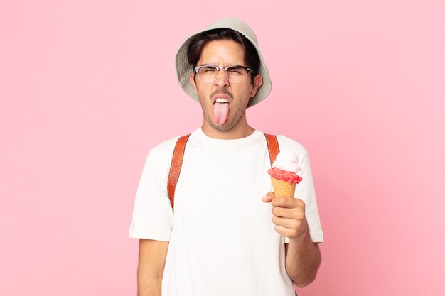 Jovem hispânico se sentindo enojado e irritado, com a língua de fora e segurando um sorvete