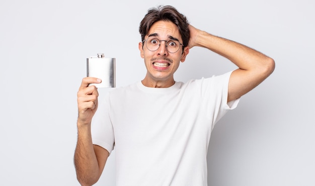 Foto jovem hispânico se sentindo estressado, ansioso ou assustado, com as mãos na cabeça. conceito de garrafa de álcool