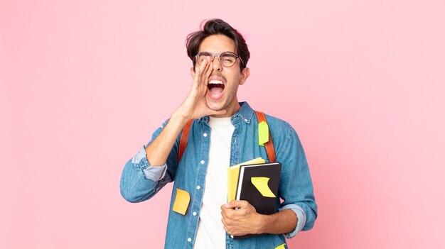 Jovem hispânico se sentindo feliz, dando um grande grito com as mãos perto da boca. conceito de estudante