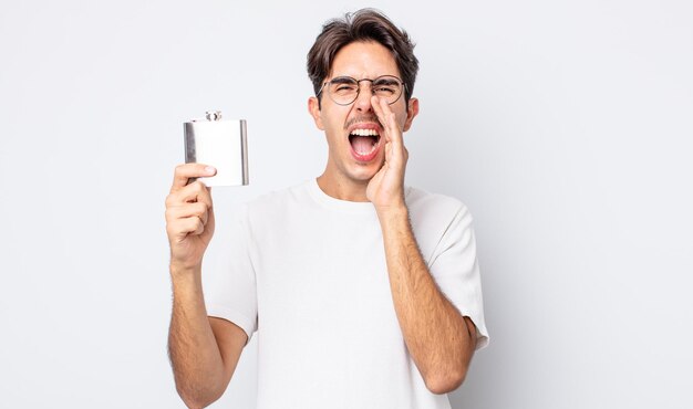 Jovem hispânico se sentindo feliz, dando um grande grito com as mãos perto da boca. conceito de frasco de álcool