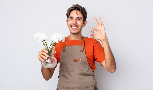 Jovem hispânico se sentindo feliz mostrando aprovação com o conceito de florista de gesto bem