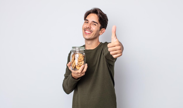 Jovem hispânico se sentindo orgulhoso, sorrindo positivamente com os polegares para cima. conceito de biscoitos