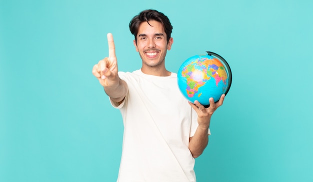 jovem hispânico sorrindo com orgulho e confiança fazendo o número um e segurando um mapa do globo terrestre