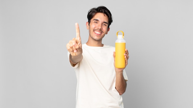 Jovem hispânico sorrindo com orgulho e confiança fazendo o primeiro com uma garrafa térmica de café