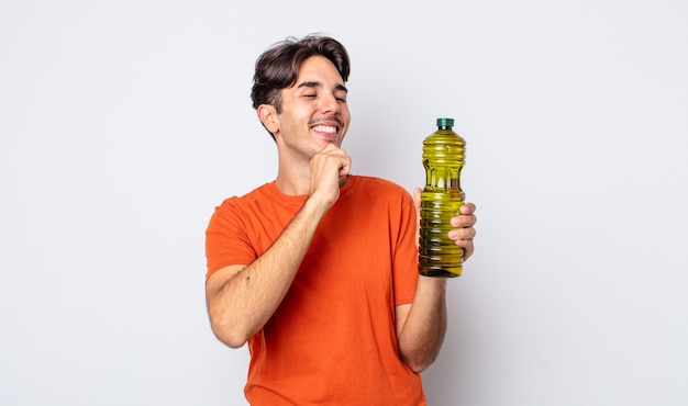 Foto jovem hispânico sorrindo com uma expressão feliz e confiante com a mão no queixo. conceito de azeite