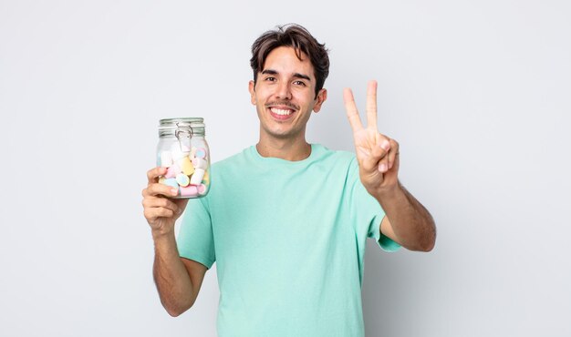 Jovem hispânico sorrindo e parecendo amigável, mostrando o número dois. conceito de doces de geléia