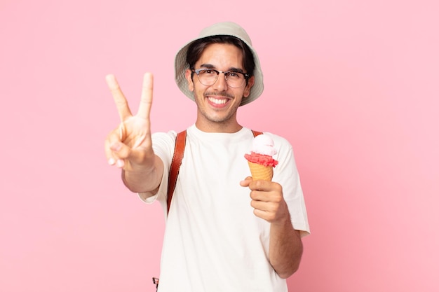 Jovem hispânico sorrindo e parecendo amigável, mostrando o número dois e segurando um sorvete