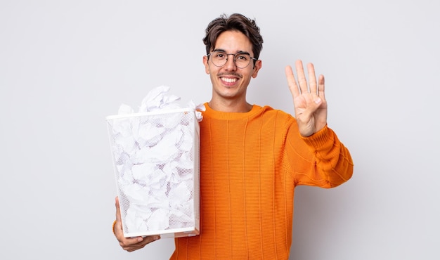 Jovem hispânico sorrindo e parecendo amigável, mostrando o número quatro. conceito de lixo de bolas de papel