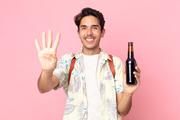 Jovem hispânico sorrindo e parecendo amigável, mostrando o número quatro e segurando uma garrafa de cerveja