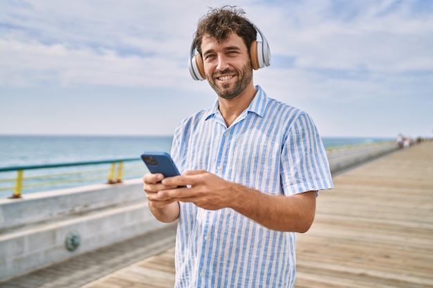 Jovem hispânico sorrindo feliz ouvindo música no passeio