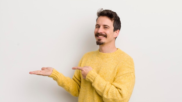 Jovem hispânico sorrindo sentindo-se feliz despreocupado e satisfeito apontando para o conceito ou ideia no espaço da cópia ao lado