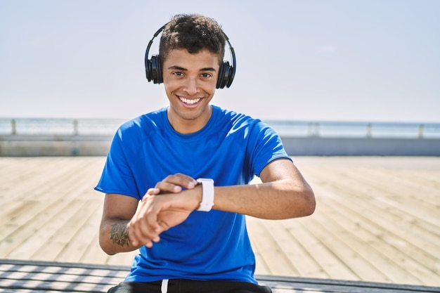 Jovem hispânico treinando usando relógio inteligente ao ar livre