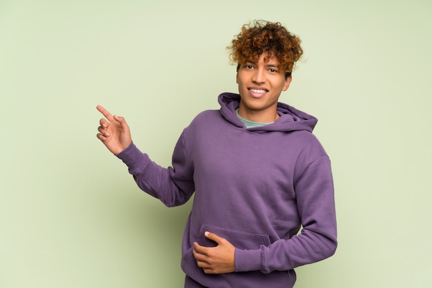 Jovem, homem americano africano, sobre, isolado, parede verde, apontar dedo, ao lado