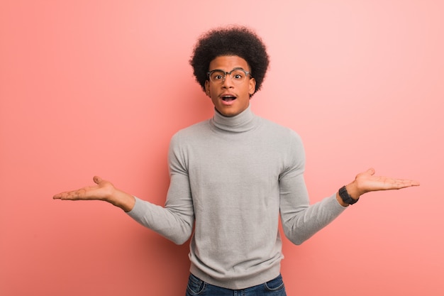 Jovem, homem americano africano, sobre, um, parede cor-de-rosa, confuso, e, duvidoso