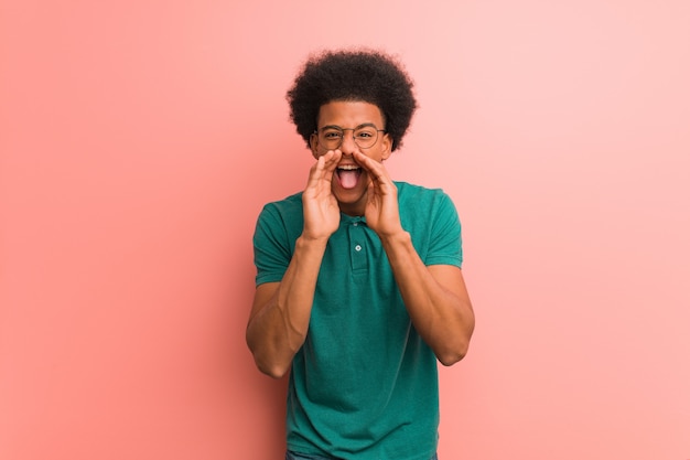 Jovem, homem americano africano, sobre, um, parede cor-de-rosa, shouting, algo, feliz, frente