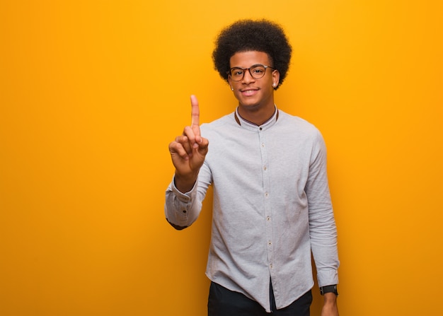 Jovem, homem americano africano, sobre, um, parede laranja, mostrando, numere um