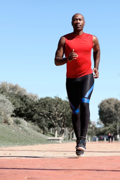 Jovem homem ativo com fones de ouvido jogging ao ar livre