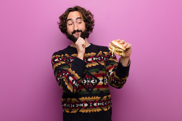 Jovem homem barbudo louco comendo um hambúrguer